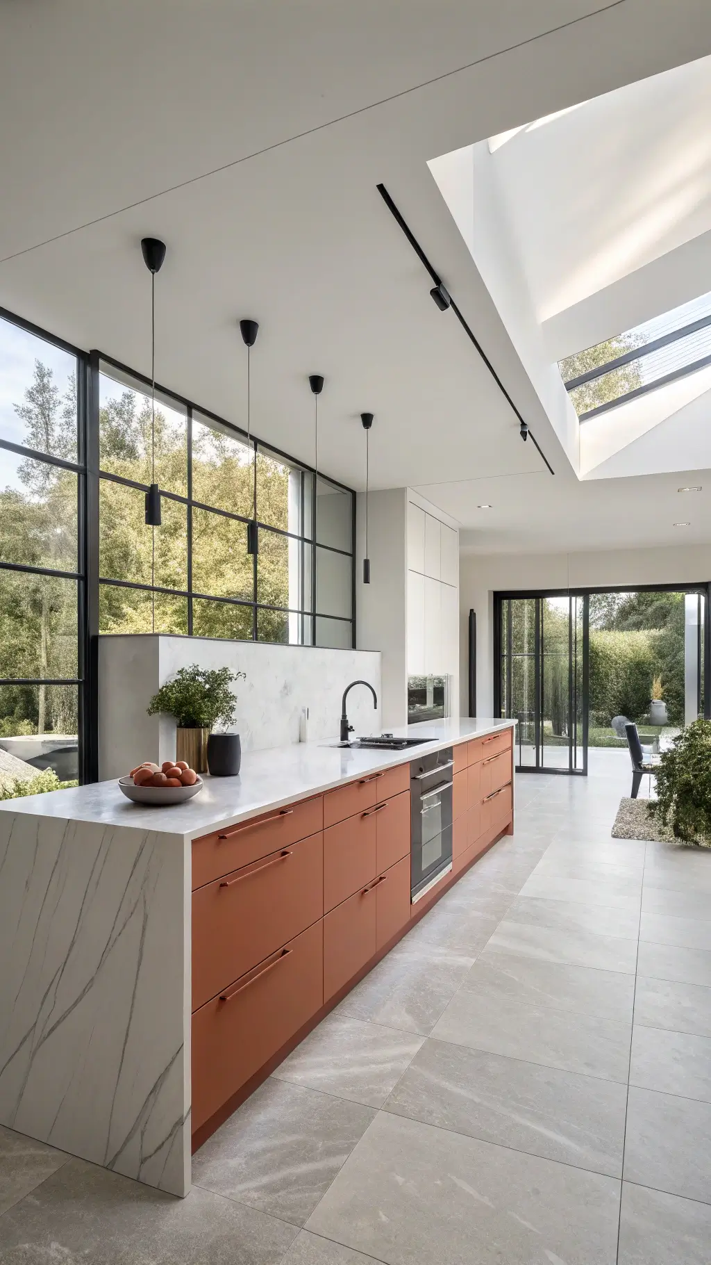 Bird's eye view of a modern minimalist open-plan kitchen with terracotta island cabinets, sleek marble countertops, floor-to-ceiling windows and matte black fixtures, styled with black stoneware, greenery, and geometric textiles in morning light.