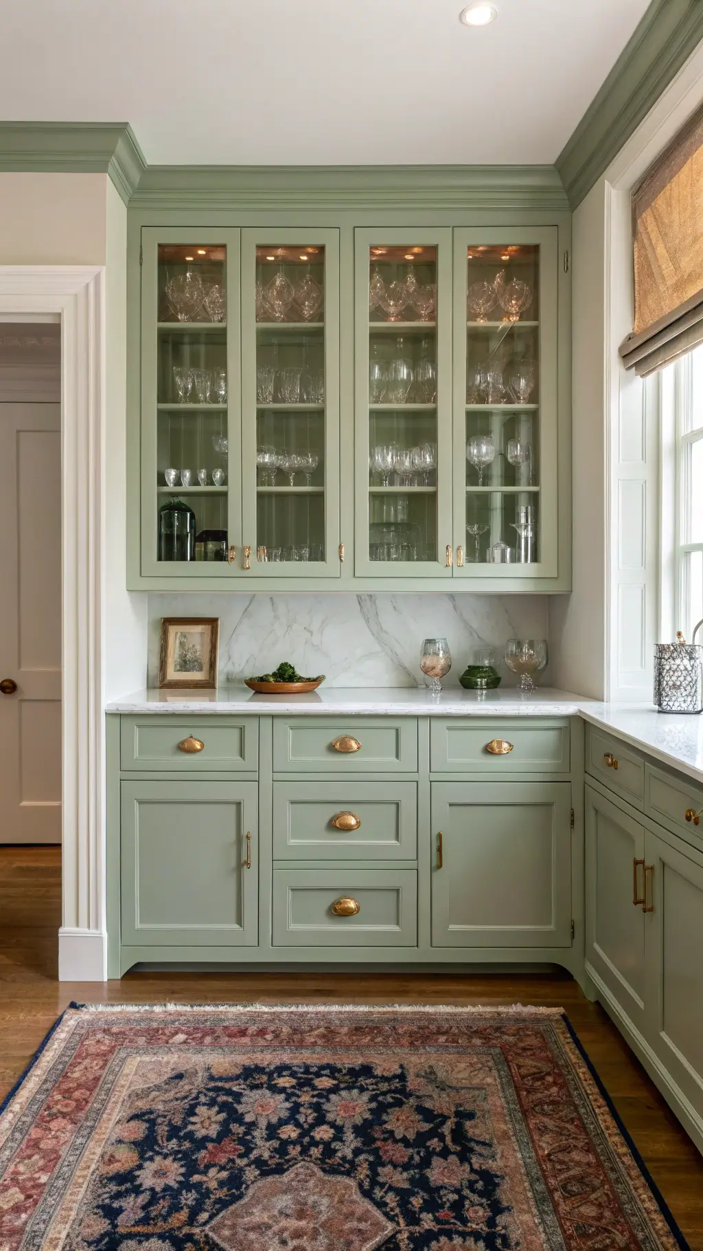 Victorian-era butler's pantry with sage green glass-front cabinet, marble countertop, brass hardware, and Persian runner under soft northern light.